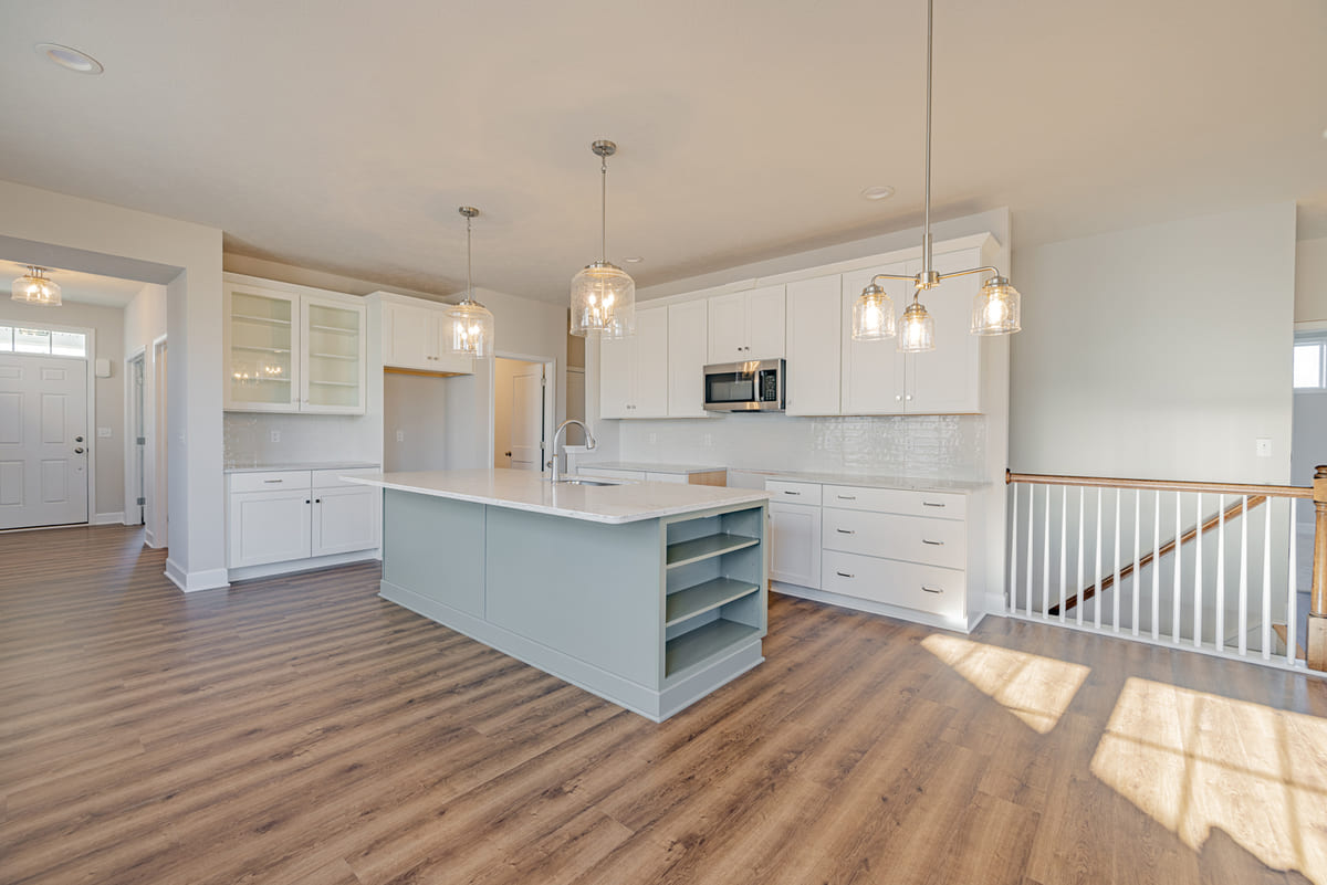 View of kitchen with island and white cabinetry in The Cottages of Canandaigua new home community